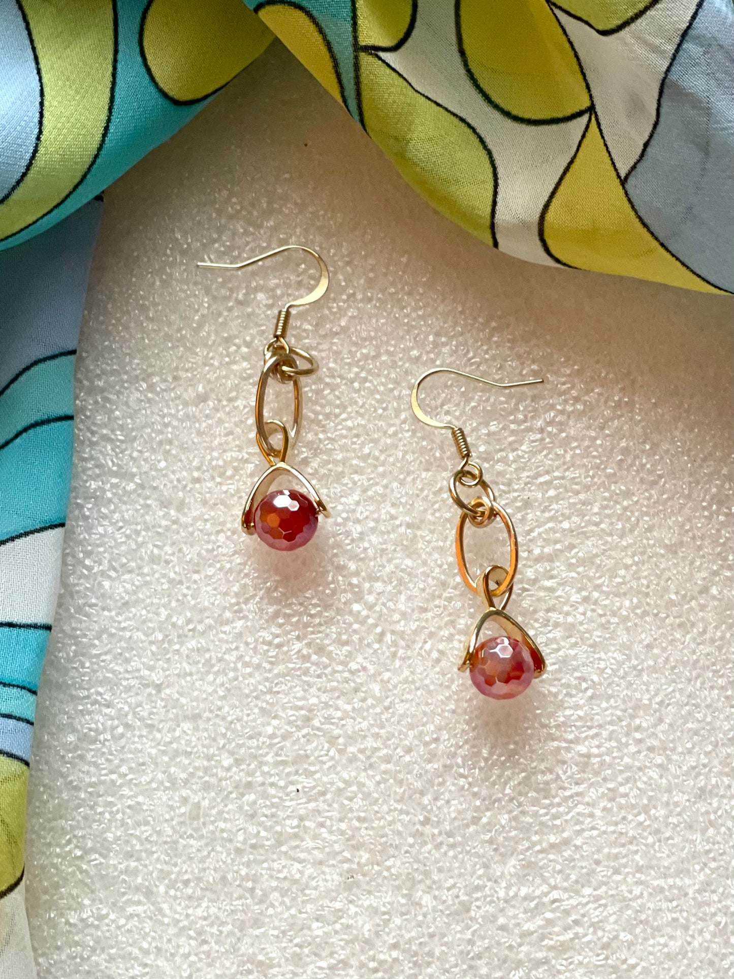 25 E24 Red-orange faceted dangle on gold earring
